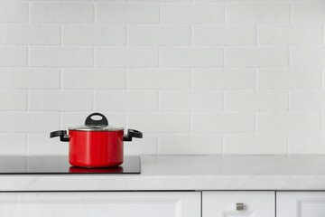 Saucepot on induction stove in kitchen, space for text
