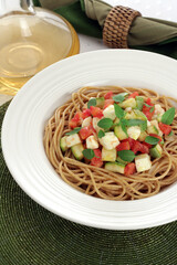 spaghetti pasta with zucchini sauce, white cheese, tomatoes and basil