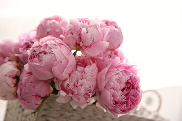 Basket with beautiful pink peonies in kitchen, closeup