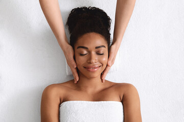 Top view of relaxed black woman having facial massage