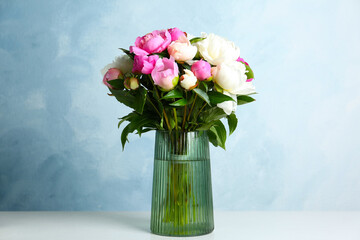 Bouquet of beautiful peonies in vase on white table