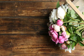 Bouquet of beautiful peonies on wooden table, top view. Space for text