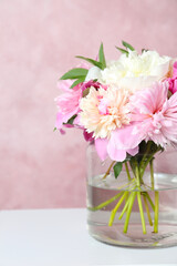 Bouquet of beautiful peonies in vase on white table