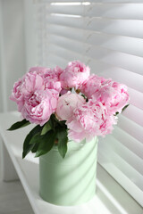 Bouquet of beautiful peonies on window sill
