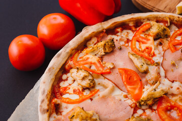 Tasty italian pizza and cooking ingredients tomatoes basil on black concrete background. Hot pepperoni pizza.