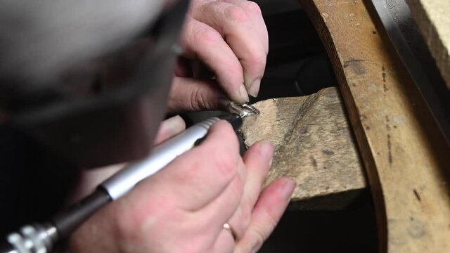 Jeweler in professional jewelry workshop engraves wedding ring with engraver