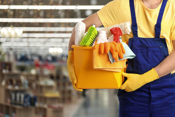 Male janitor with cleaning supplies in shopping mall, closeup. Space for text