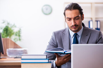 Young male businessman reading books at workplace