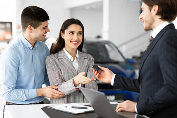 Salesman Giving Auto Key To Family Couple