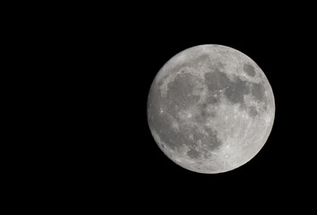 Super moon. The moon is full (or nearly full). Craters and mountains are clearly visible at the edges. There is room for text to the left.