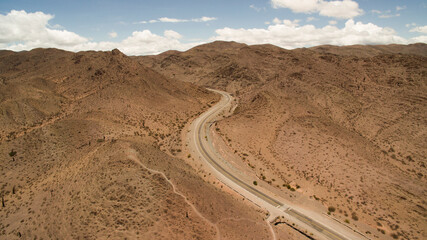 Transport. Aerial view of the empty desert highway crossing the arid rocky mountains. 