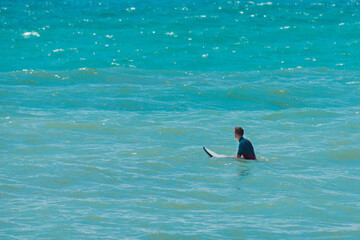 Surfer with surfboard on water. Blue sea surface background