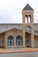 Church facade with glass front doors and modern belfry tower against cloudy sky