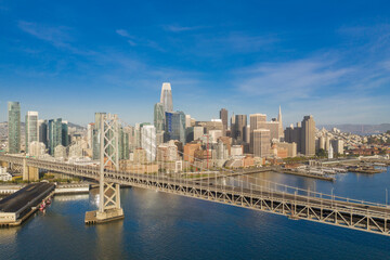 Fototapeta premium Widok z lotu ptaka na panoramę San Francisco w Kalifornii o wschodzie słońca. Dużo miejsca na kopię w błękitne niebo. Most zatokowy na pierwszym planie.