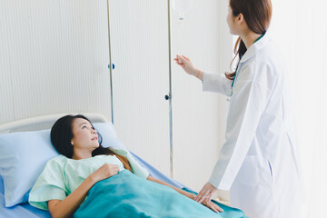 Asian woman doctor visits the patient lying in the hospital bed.