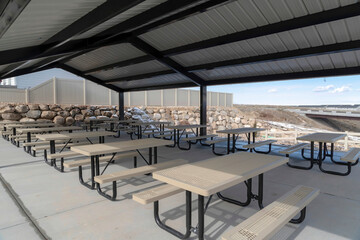 Tables with seats inside a gabled roof pavilion in South Jordan City in Utah