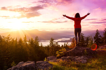 Adventure Girl on top of a Mountain with Canadian Nature Landscape in the Background during colorful sunset. Taken on Bowen Island, near Vancouver, British Columbia, Canada.