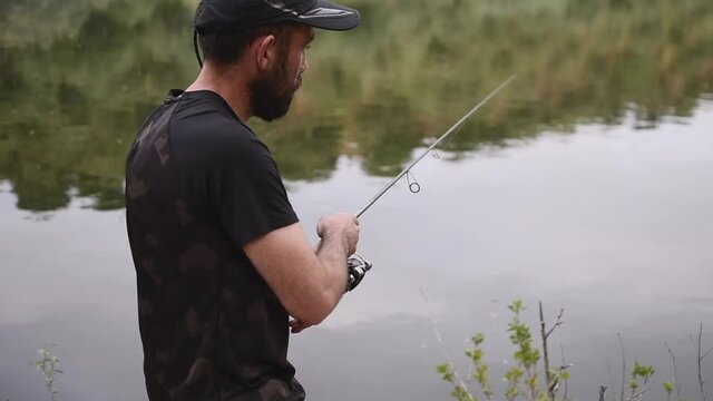Fisherman collecting the thread of the fishing rod while fishing trout in the river
