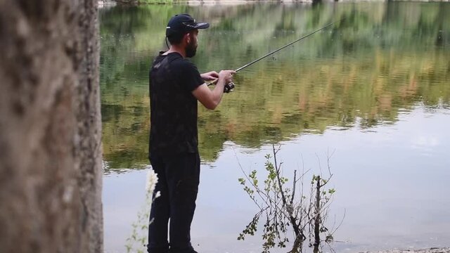 Fisherman collecting the thread of the fishing rod while fishing trout in the river