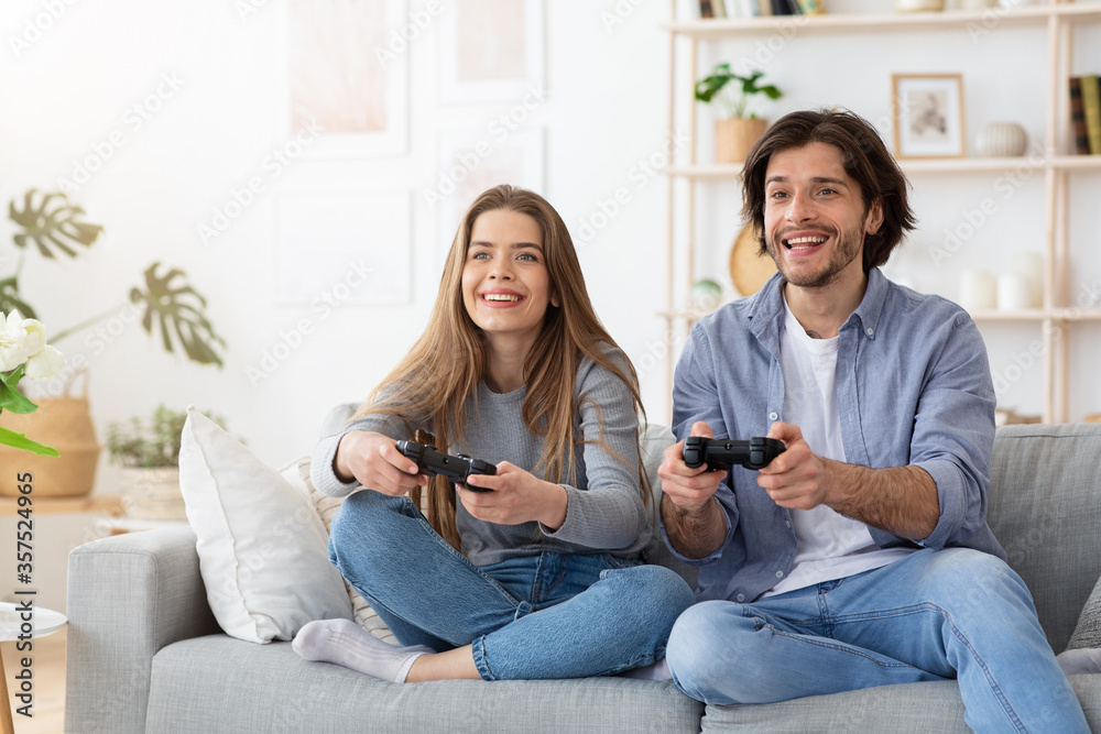 Wall mural Excited funny couple playing video games at home