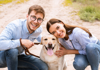 Portrait of happy young couple rubbing their labrador