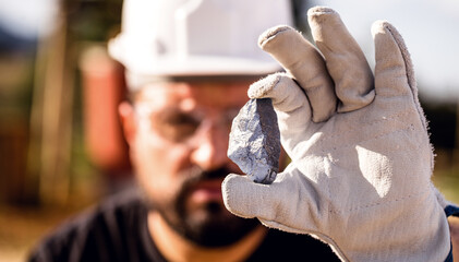 miner man holding a silver stone, point focus. Gemstone mining concept.