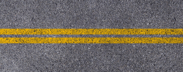 Top view of Double yellow lines on asphalt street roadway surface texture background.