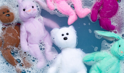 Soak rabbit doll with  toy teddy bear in laundry detergent water dissolution before washing.  Laundry concept