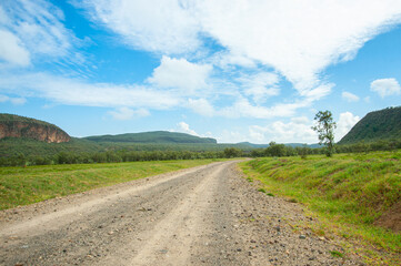Fototapeta na wymiar African dirty road and blue cloudy sky