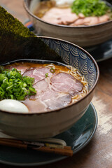 asian ramen with pork meat noodles chive broth egg and nori on a traditional bowl with colorful shallow background
