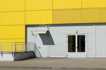 Fototapeta na wymiar Rear entrance, two doors to a modern shopping center, shop. Yellow sunny bright building warehouse. There is no one, deserted.