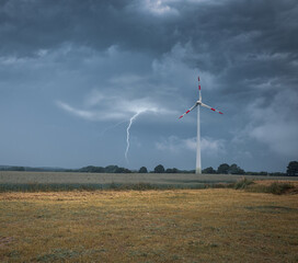 a lightning strikes the ground next to a wind turbine