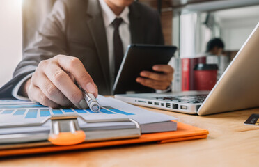 Businessman using a tablet and computer to analysis graph company financial at home office in the morning.