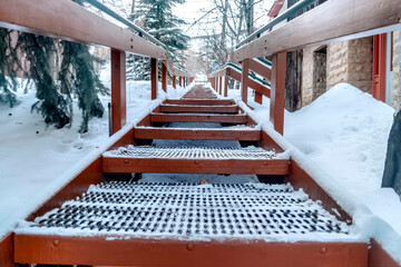 Focus on grate metal treads of outdoor stairs against snowy hill in winter