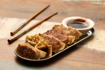 gyoza on silver plate wooden table chopsticks and soy sauce