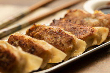 gyoza on silver plate wooden table chopsticks and soy sauce