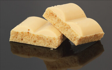 White chocolate on black background. Macro with bubble aerated dessert.