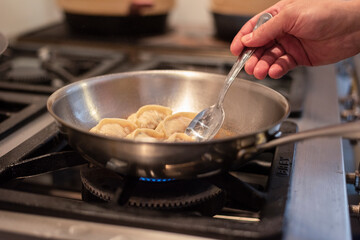 chef preparing asian gyoza on oven and pan with water