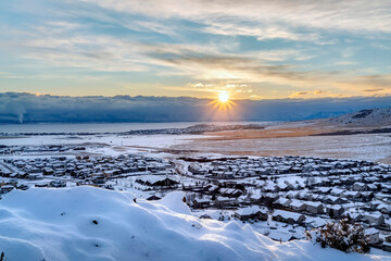 Beautiful sunrise in Draper Utah with snowy hills lake and houses in winter