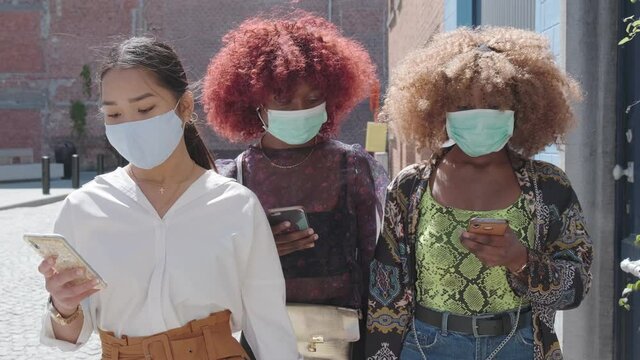 young women walking in medical mask with cellphones during the coronavirus COVID-19 pandemic