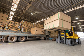 wood pallet forklift driving at a factory floor inside a shed loading a truck