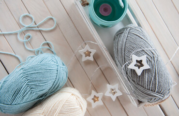 Wool yarn milky, gray, mint color lie on a light wooden table