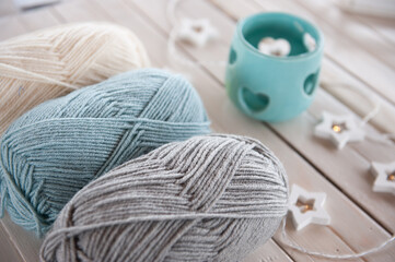 Fototapeta na wymiar Wool yarn milky, gray, mint color lie on a light wooden table
