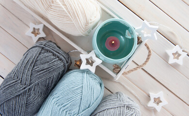 Wool yarn milky, gray, mint color lie on a light wooden table
