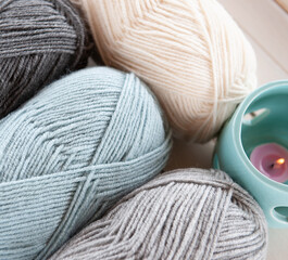 Wool yarn milky, gray, mint color lie on a light wooden table