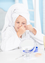 Girl wearing a towel on her head uses patches on her face and looks in the mirror