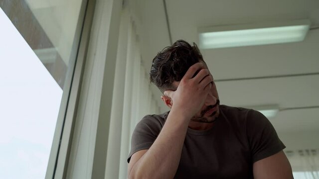 mental health, men sitting stressed by the window, in an epidemic condition covid -19, causing him to lose his job
