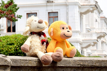 Baby stuffed toys monkey and sheep are sitting on the background of the palace © dzmitry_2014