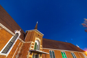 Facade of a church in Provo Utah with brick wall arched windows and steeple