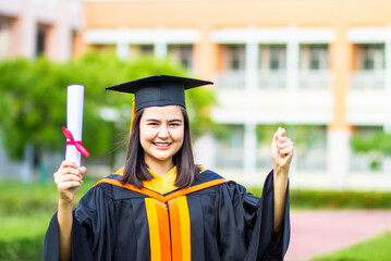 Graduation girl raises her hand to celebrate her graduation, complete with a diploma and her sense of pride and happiness.